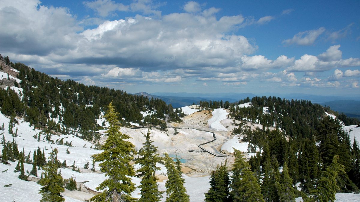 Área hidrotermal de Bumpass Hell, com passarela e solo claro entre pinheiros e neve, no Parque Nacional Vulcânico Lassen