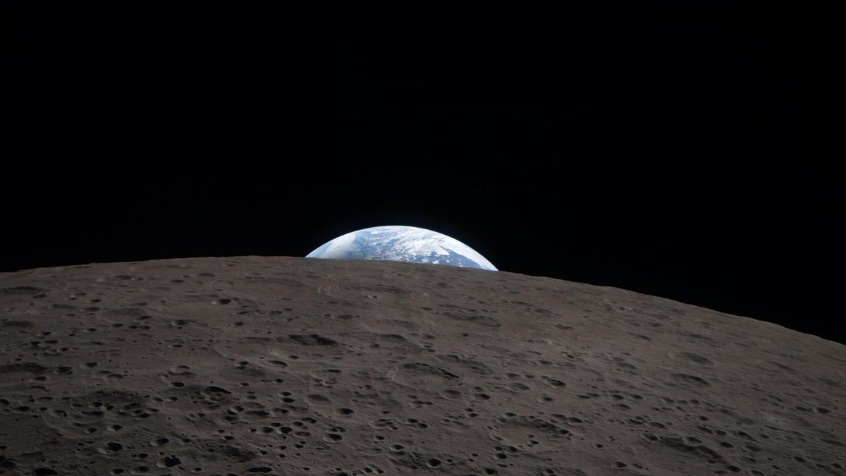 A Terra, azul e branca, aparece por trás do horizonte cheio de crateras da face oculta da Lua em imagem da Artemis 2