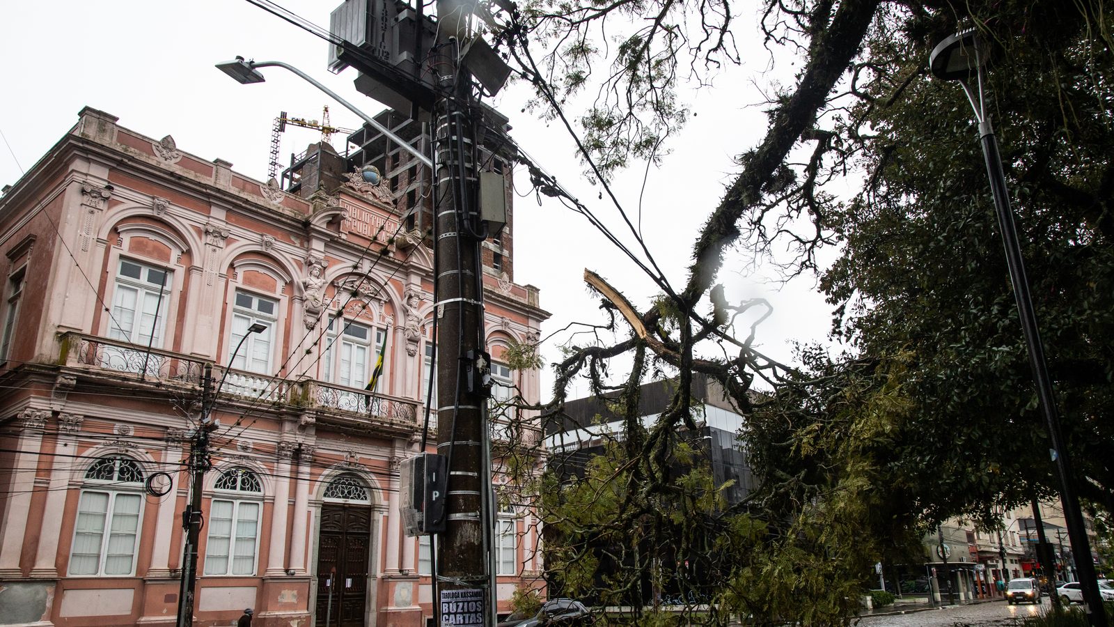 Galhos de uma árvore partida junto a um poste e aos fios numa rua de Pelotas, imagem de arquivo sobre rajadas acima de 72 km/h