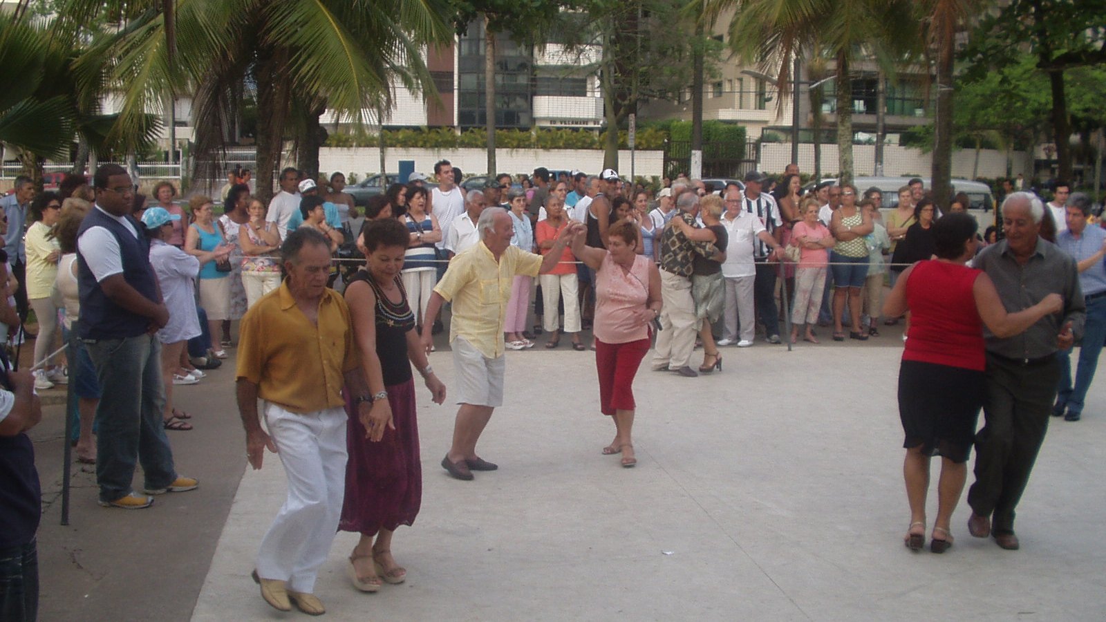 Casais de idosos dançam em baile ao ar livre na Praça do Sapo, no Canal 6, em Santos, cercados por uma roda de gente que assiste