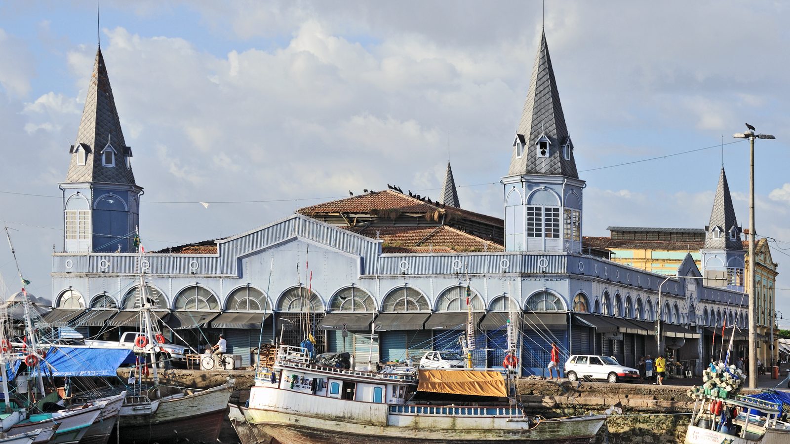Mercado Ver-o-Peso à beira da baía em Belém, com barcos de pesca encalhados na maré baixa e céu com nuvens, cenário da capital paraense onde o calor chegou a 37 °C