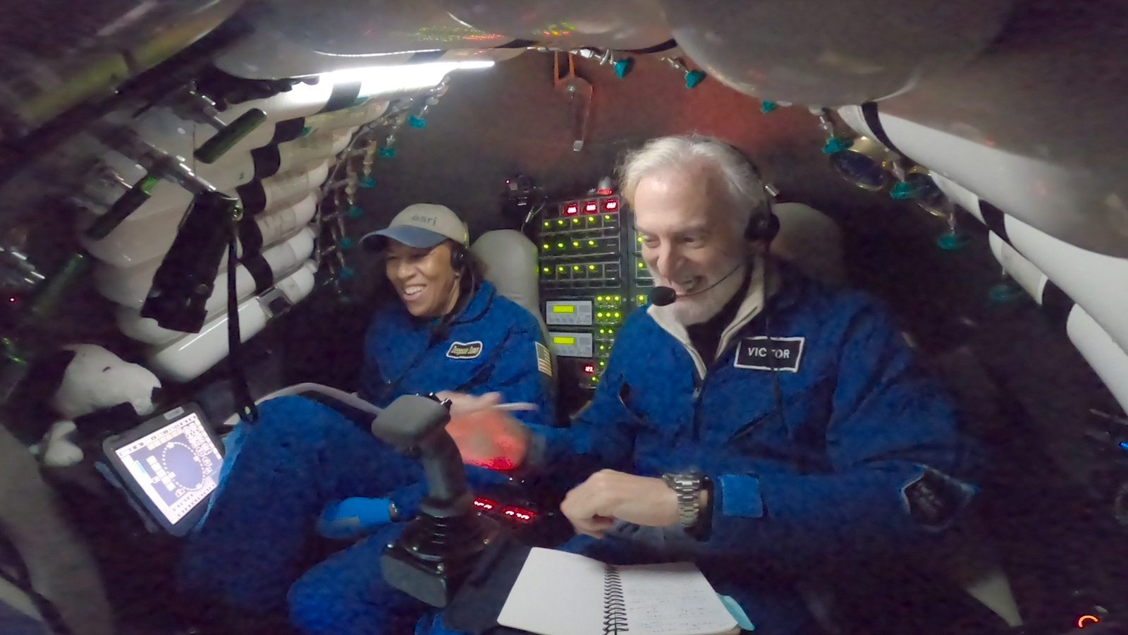 Dawn Wright e Victor Vescovo de macacão azul dentro do submersível Limiting Factor durante mergulho na fossa das marianas