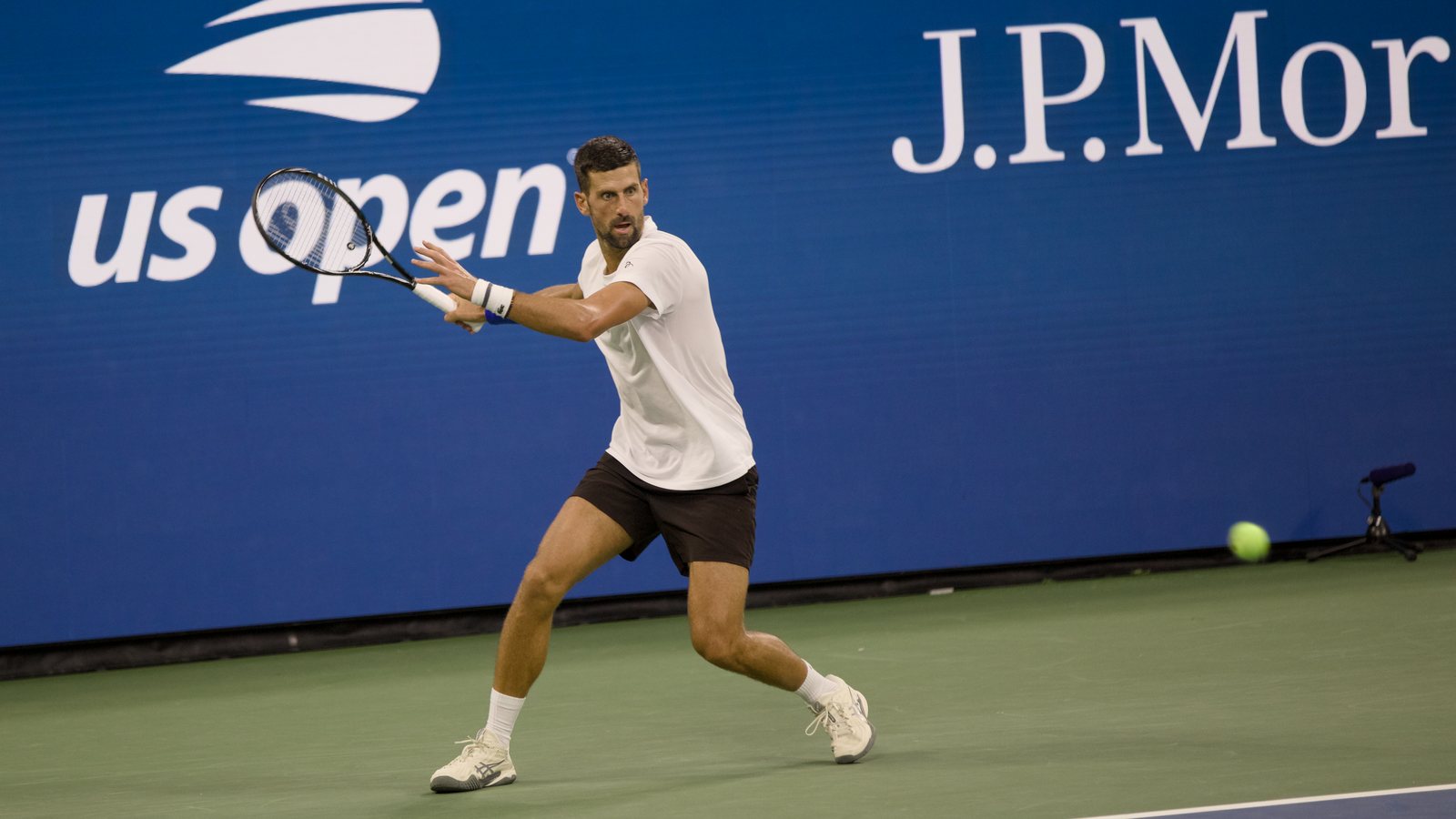 Novak Djokovic acerta um forehand na quadra Arthur Ashe, em Nova York, em agosto de 2026, com o público ao fundo