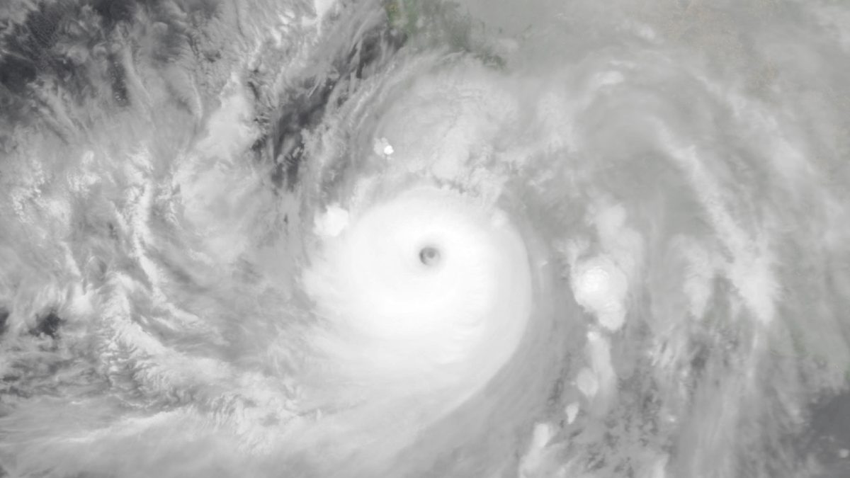 Imagem de satélite do furacão Simon com o olho escuro no centro de uma espiral branca, e a costa do México e o Golfo da Califórnia no alto à esquerda
