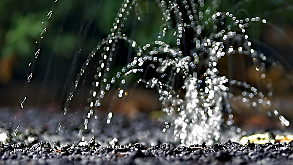 Gotas de chuva batendo numa poça rasa e espirrando água para cima