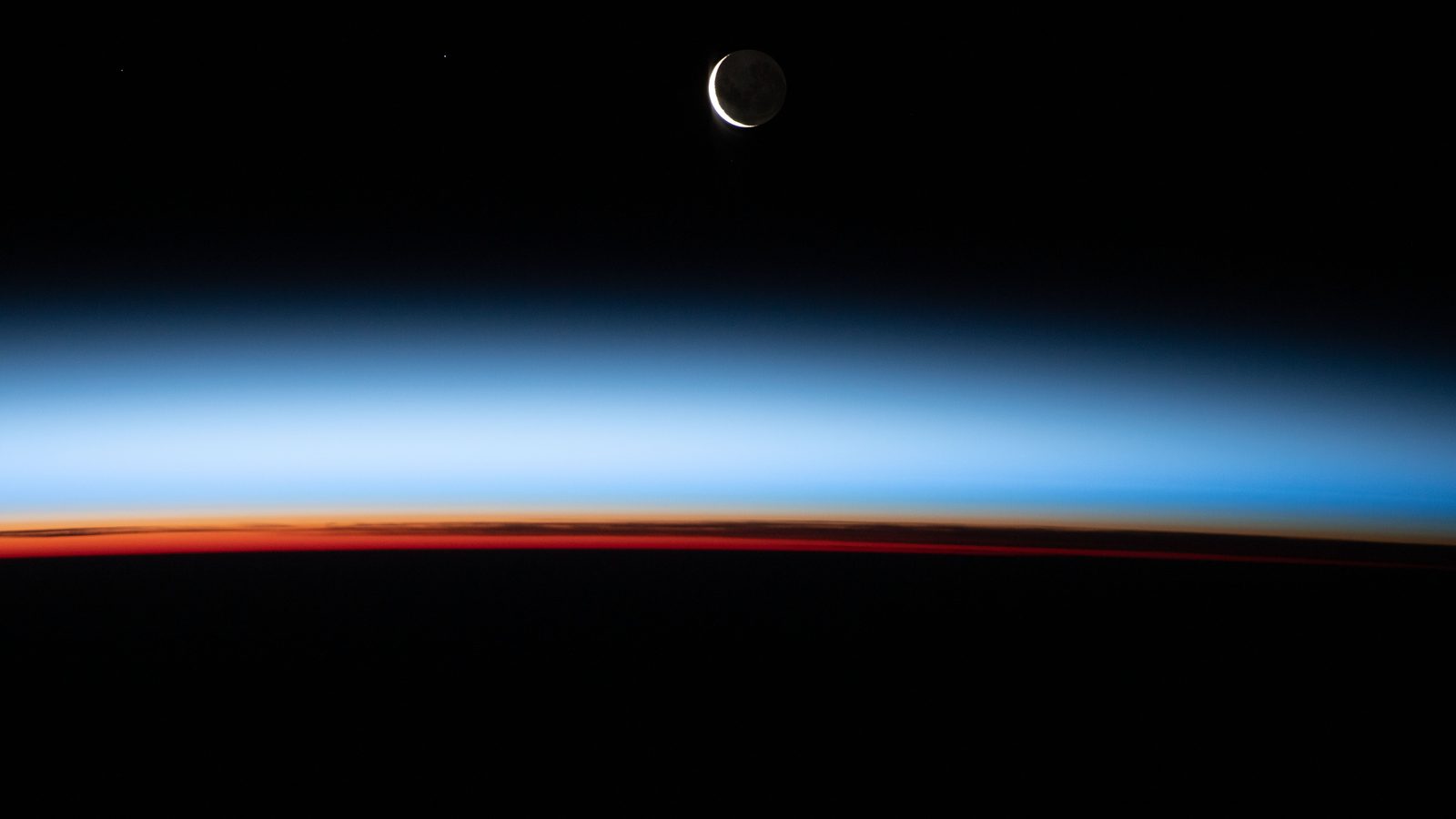 Lua crescente fina vista da Estação Espacial Internacional sobre o horizonte da Terra no pôr do Sol orbital, a Lua tem fases porque vemos partes diferentes da metade acesa