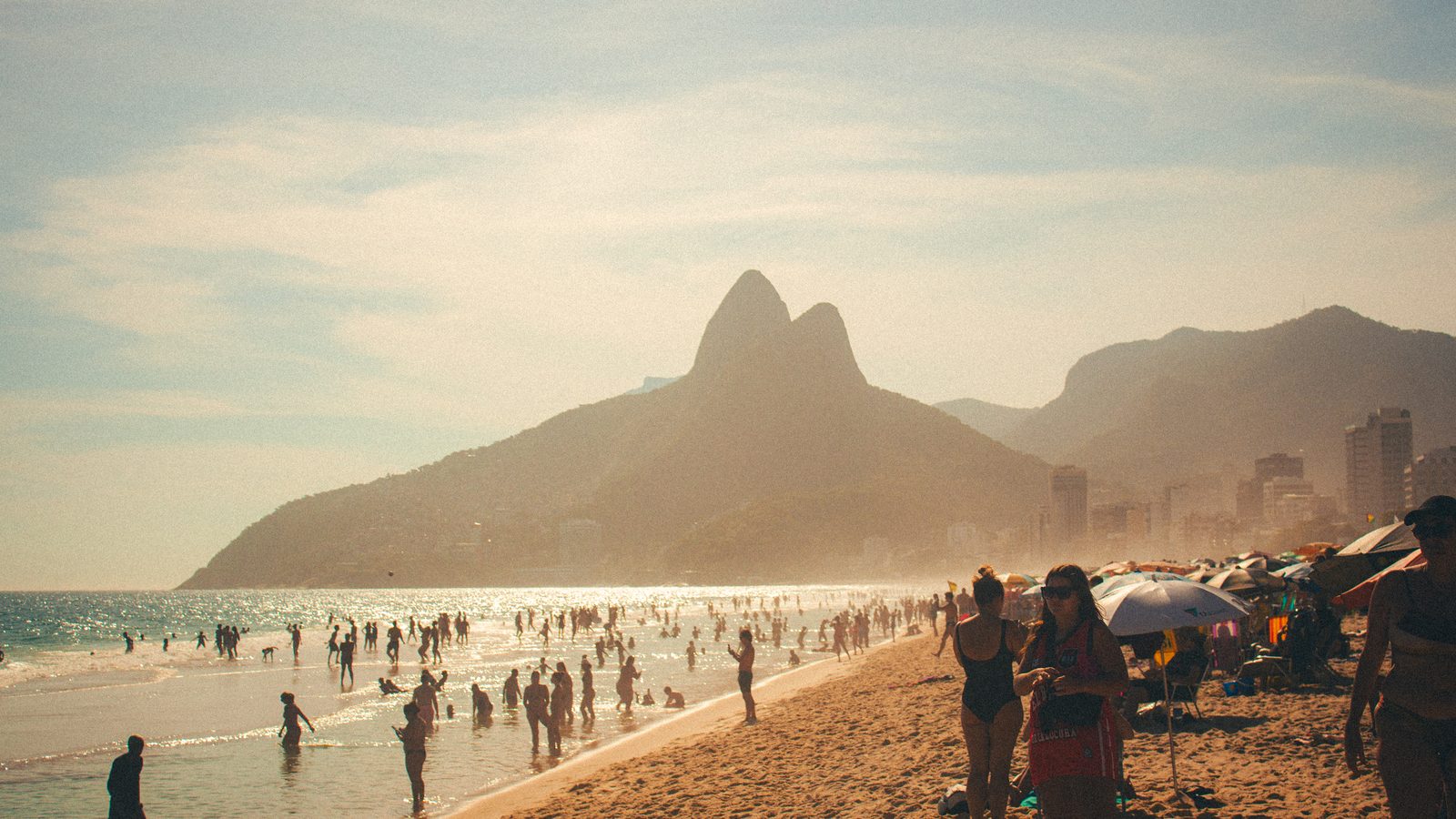 Banhistas na areia e no mar da praia de Ipanema, no Rio, sob sol forte, cenário em que o índice UV pede proteção