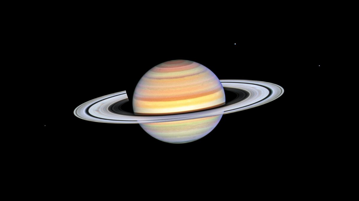 Saturno fotografado pelo Hubble em outubro de 2023, com faixas de nuvens alaranjadas e os anéis inclinados