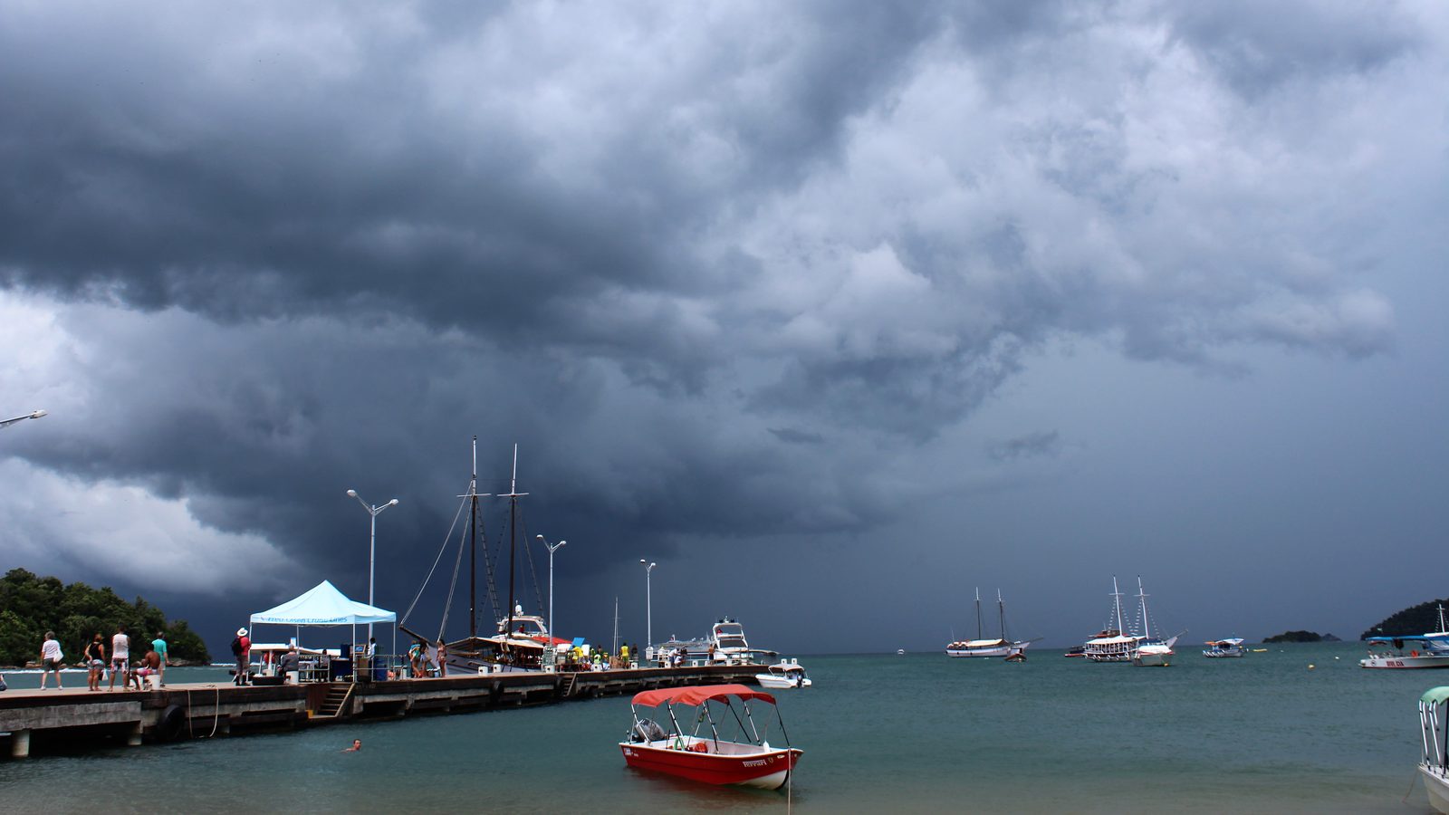 Nuvens escuras de tempestade se aproximando da Vila do Abraão, em Ilha Grande, com barcos no mar, antes do cheiro de chuva