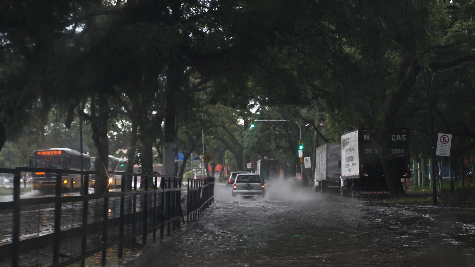 Carro levanta água numa avenida alagada de Porto Alegre sob temporal, cena do tipo de risco de enxurrada que o Cemaden prevê para o fim de semana