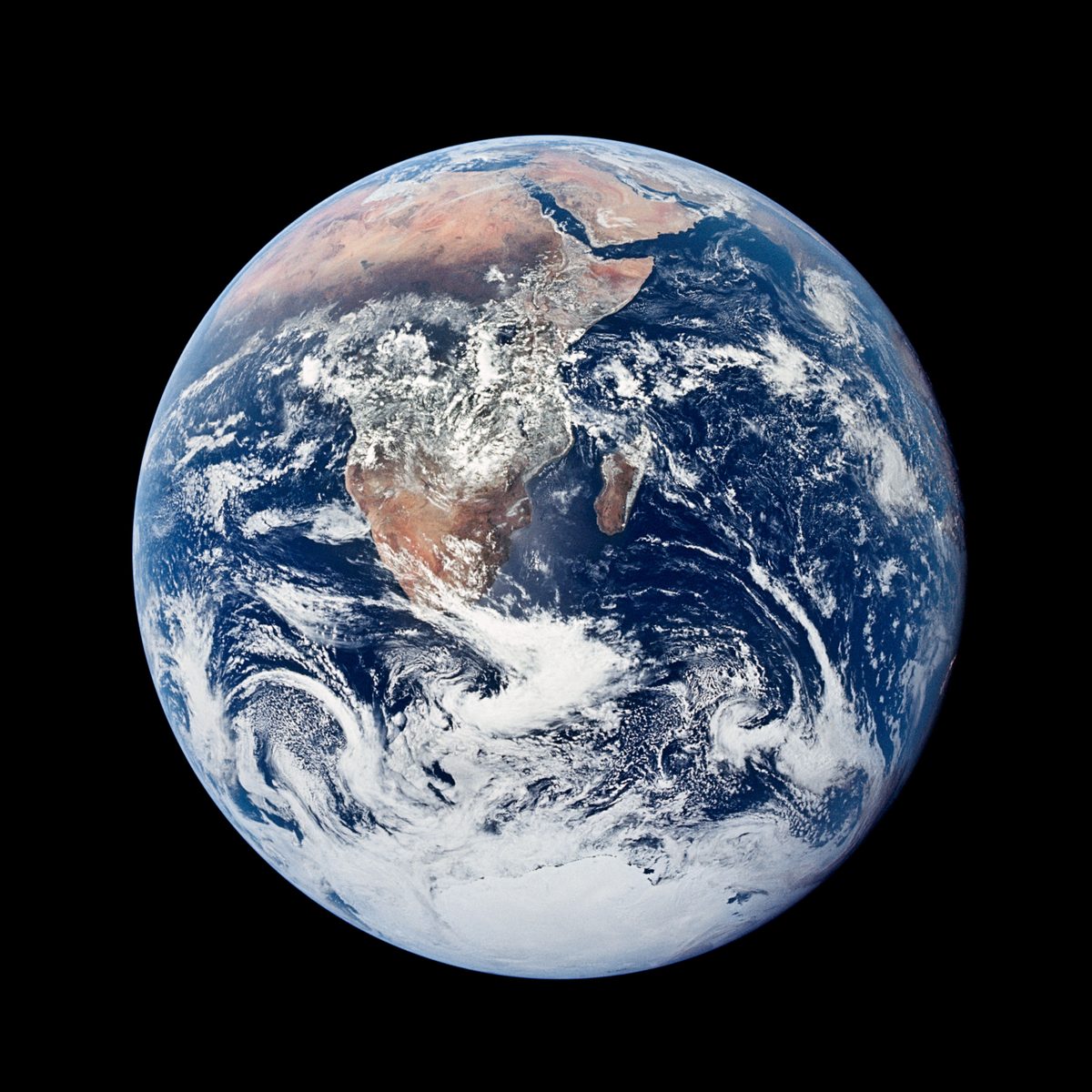 A Terra inteira vista pela tripulação da Apollo 17, com a África, a Arábia e o gelo da Antártida cercados por nuvens, contra o espaço preto
