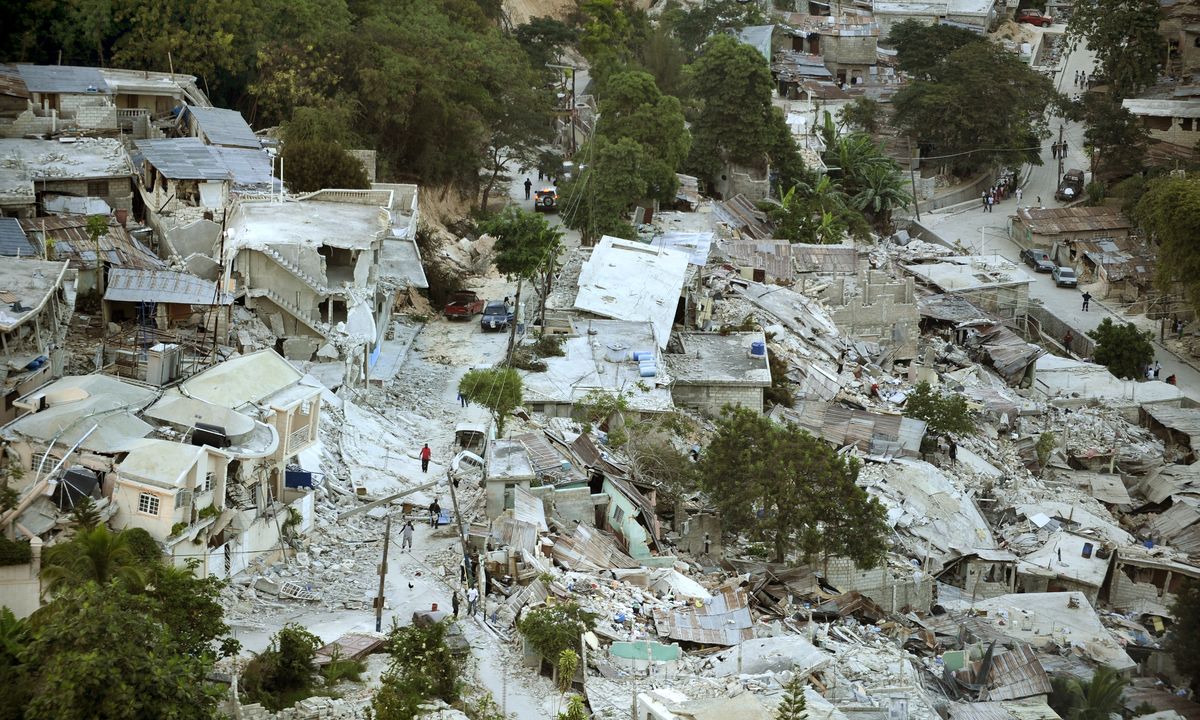 Encosta de Porto Príncipe com dezenas de casas de concreto desabadas umas sobre as outras entre árvores, três dias depois do terremoto de 2010